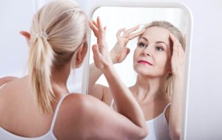Pretty Middle Aged Woman Looking at Her Forehead in the Mirror